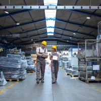 factory-workers-walking-through-large-production-hall-having-conversation
